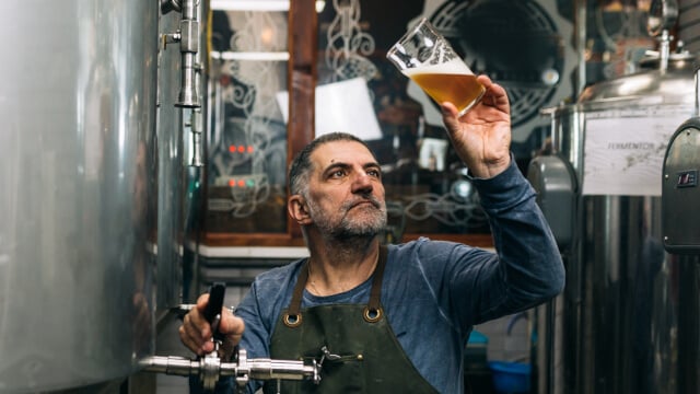 man holding and inspecting glass of beer