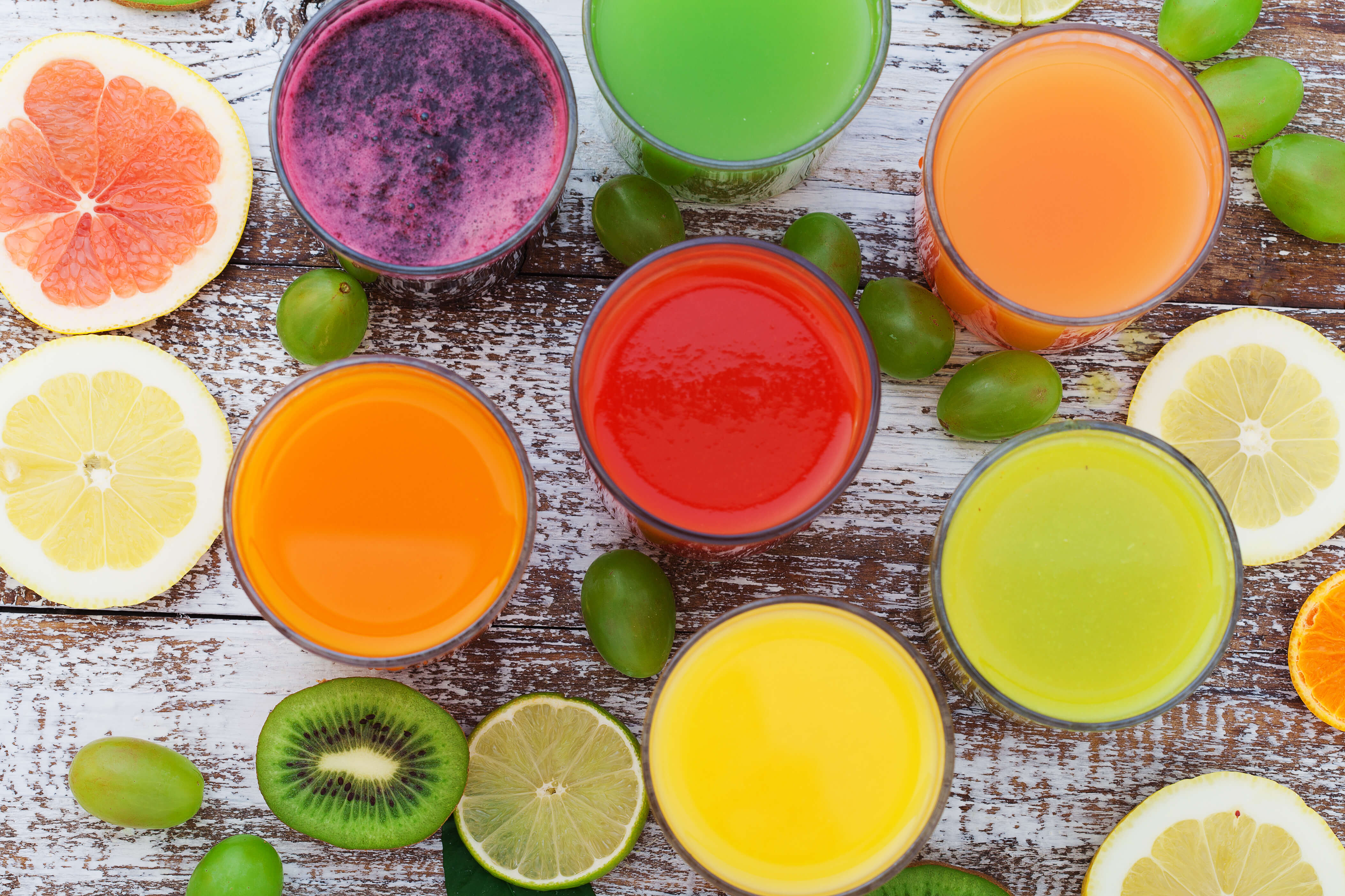 Glasses of various fresh juices on wooden desk.jpg